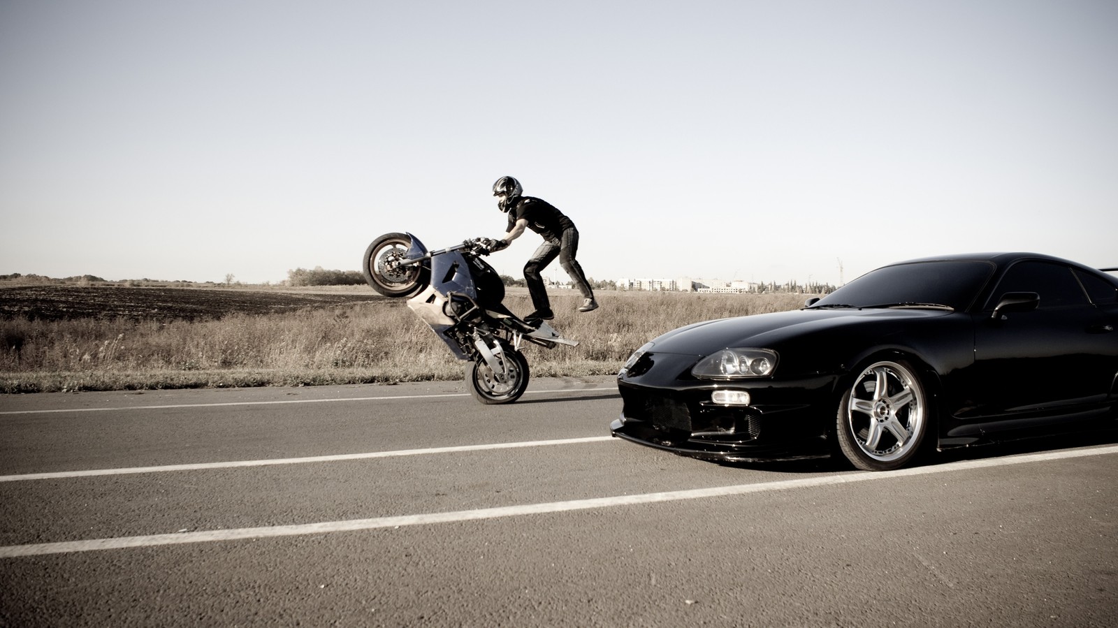 Hay un hombre montando una motocicleta en la parte trasera de un coche (acrobacias en motocicleta, motocicleta, acrobacia, coche, rueda)