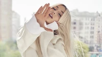 Ariana Grande showcases her stunning beauty with long blond hair and striking features, captured in a magazine photoshoot.