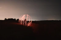 Beleuchtete Kugel in einer dunklen Landschaft unter einem sternenklaren Himmel