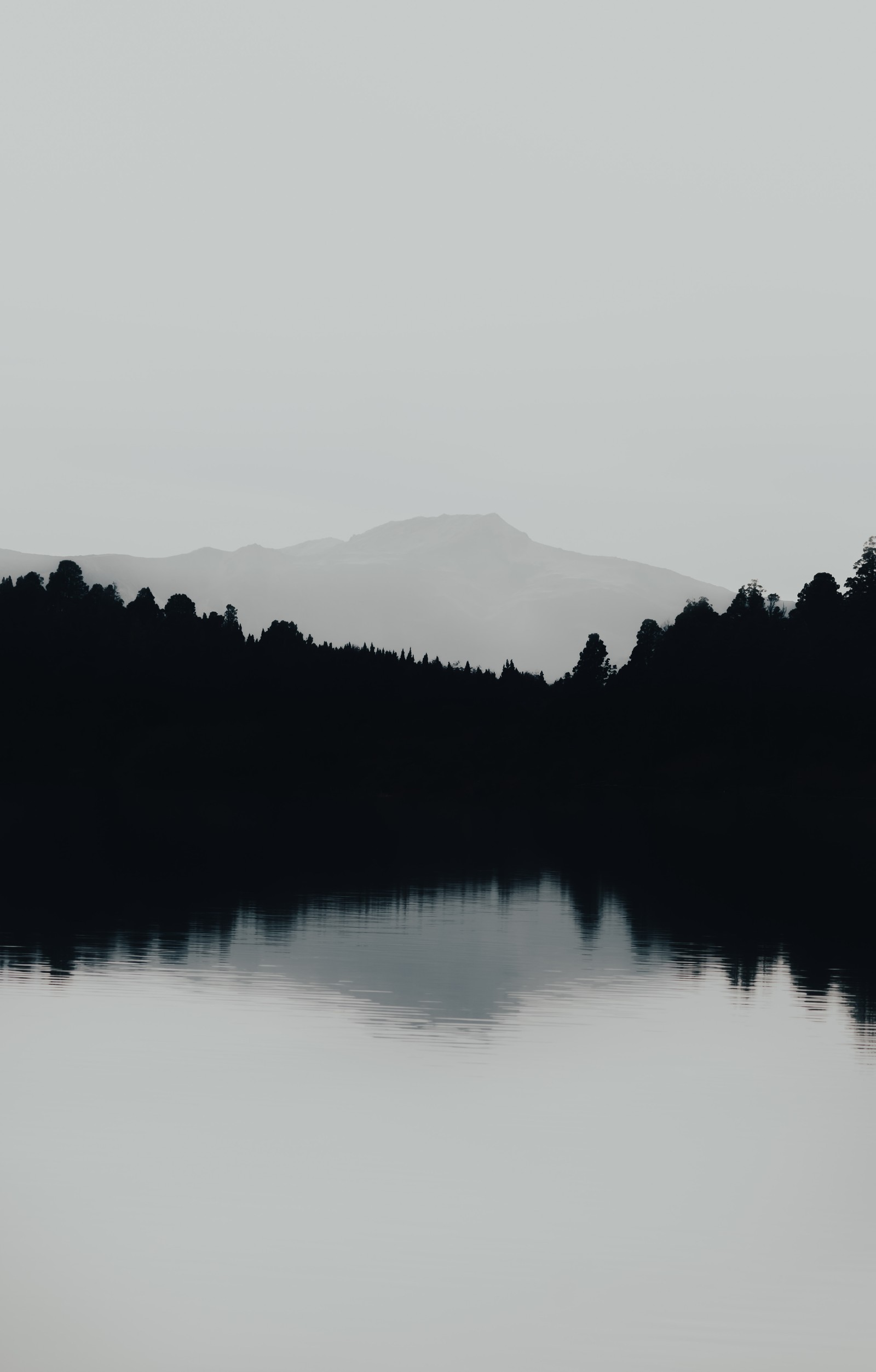 Il y a une photo en noir et blanc d'un lac avec une montagne en arrière-plan (montagne, ressources en eau, alpinisme, plan deau, réflexion)