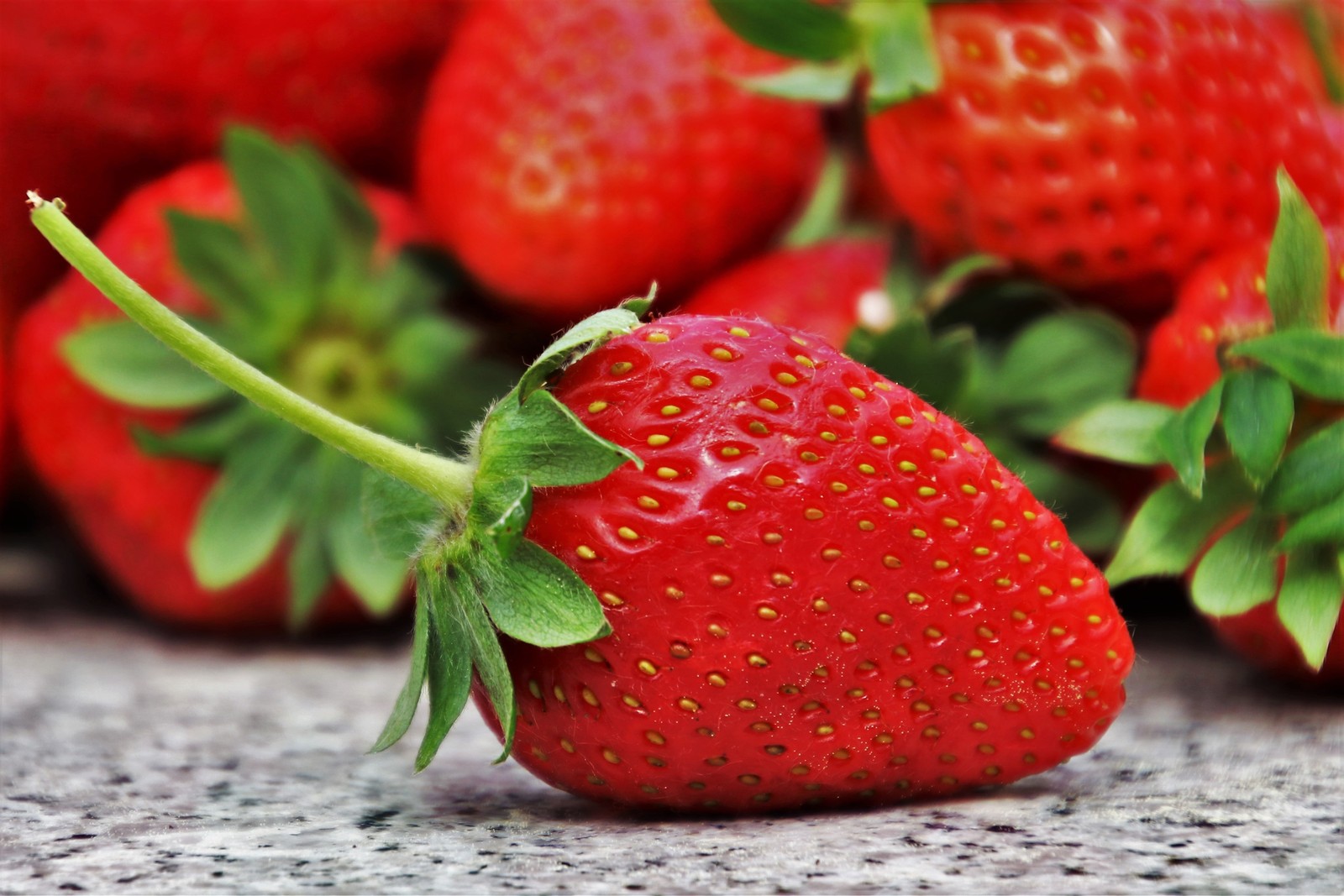 Um close de um morango com um talo e algumas outras frutas (morango, comer, fruta, alimentos naturais, baga)