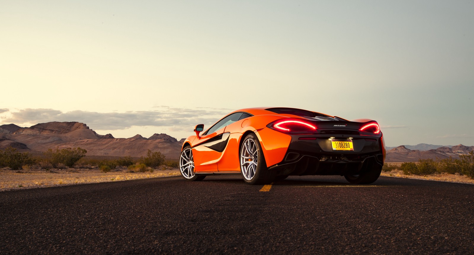 A close up of a car on a road with mountains in the background (mclaren 570s, mclaren, sports car, mclaren automotive, car)