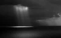 Horizon monochrome : rayons de lumière perçant à travers des nuages sombres