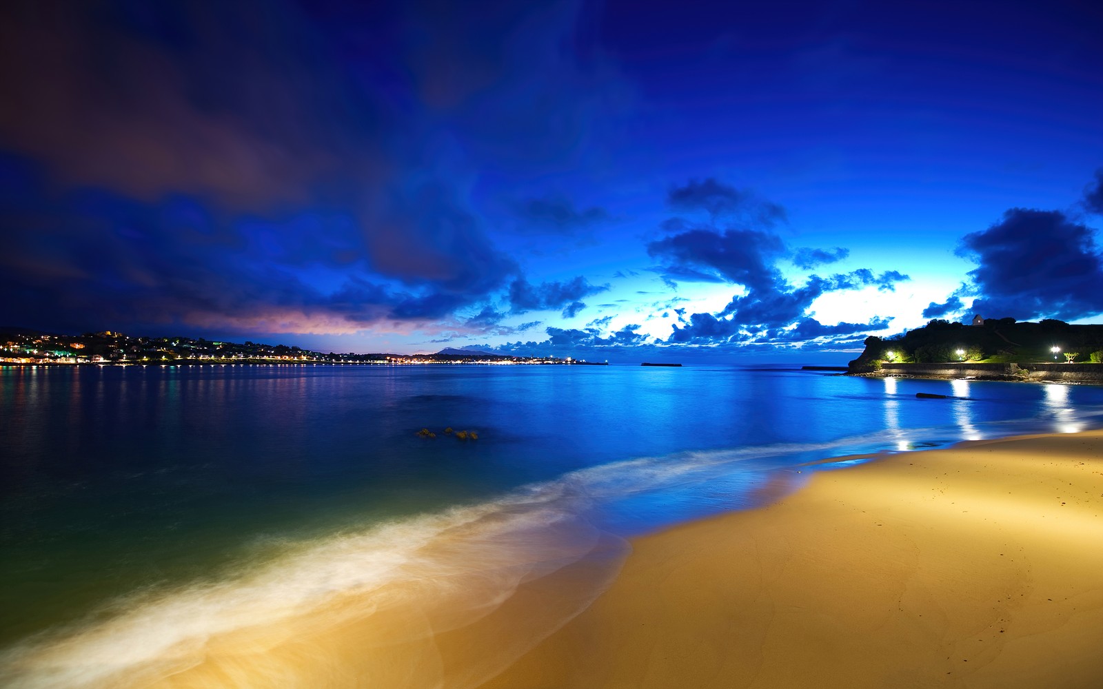 Uma vista de uma praia à noite com um céu azul (saint jean de luz, fishing port, céu azul, praia, noite)