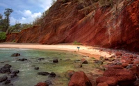 Cabo do Penhasco Vermelho: Uma paisagem costeira serena com rochas e praia de areia.