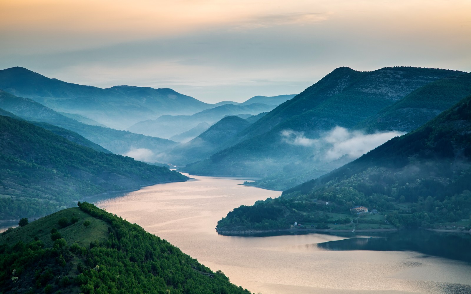 Une vue d'un lac entouré de montagnes et d'une forêt (flueve, montagne, paysage, nature, ville)