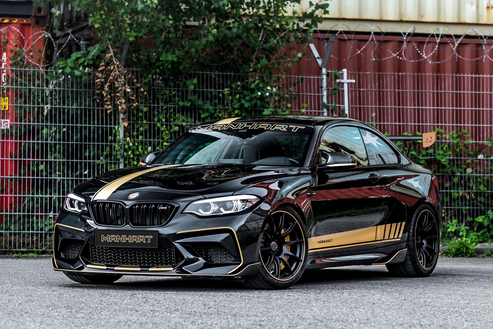 A close up of a black bmw car parked in front of a fence (manhart mh2 630, bmw m2 competition, 2022, cars, 4k wallpaper)