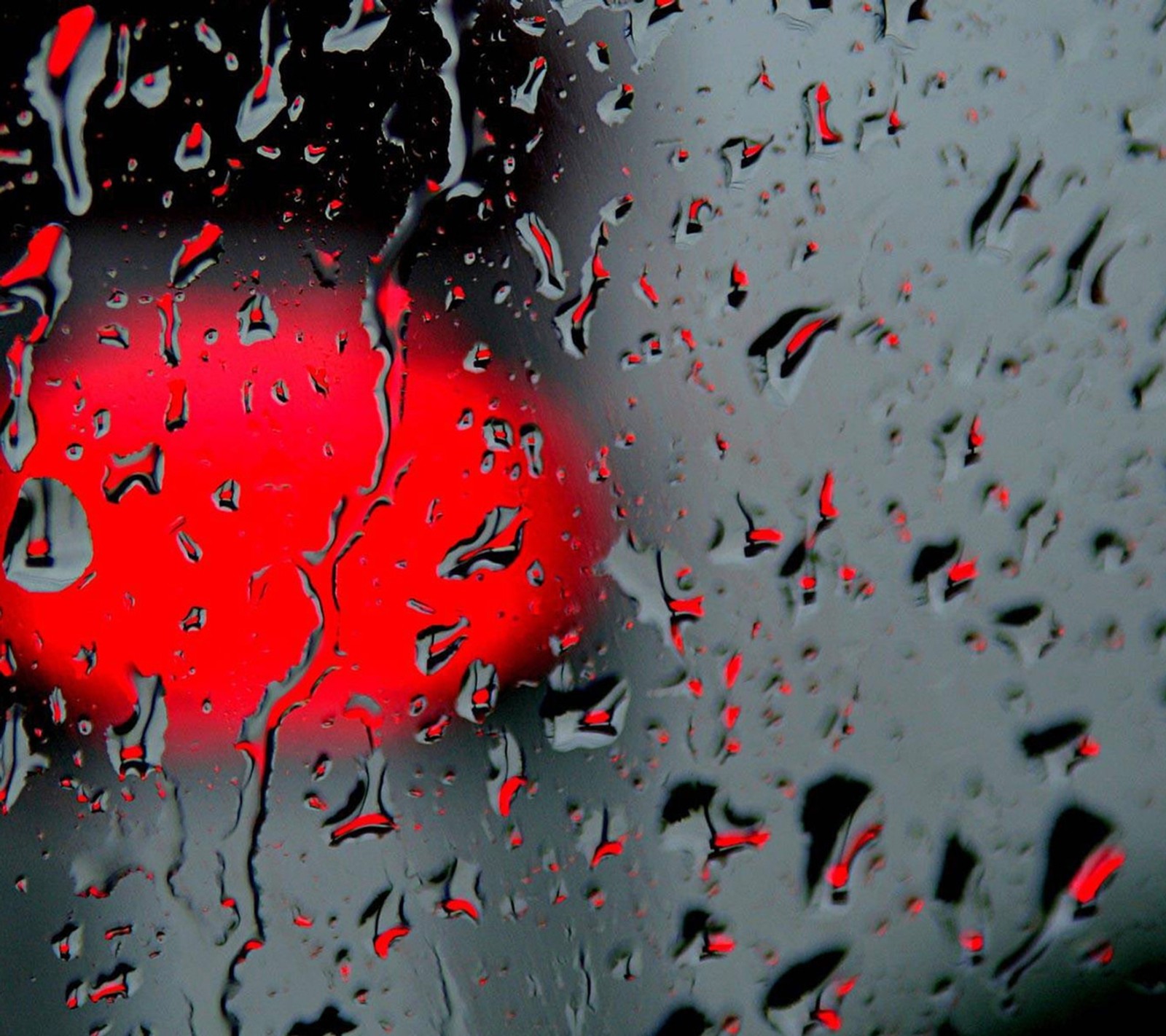 Um close de uma luz vermelha através de uma janela coberta de chuva (gotas, vermelho)