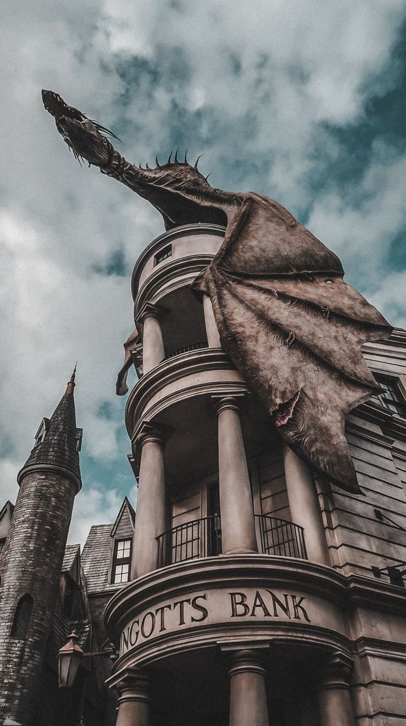 Nahaufnahme eines gebäudes mit einer drachenstatue oben drauf (hintergrundbild, harry potter)