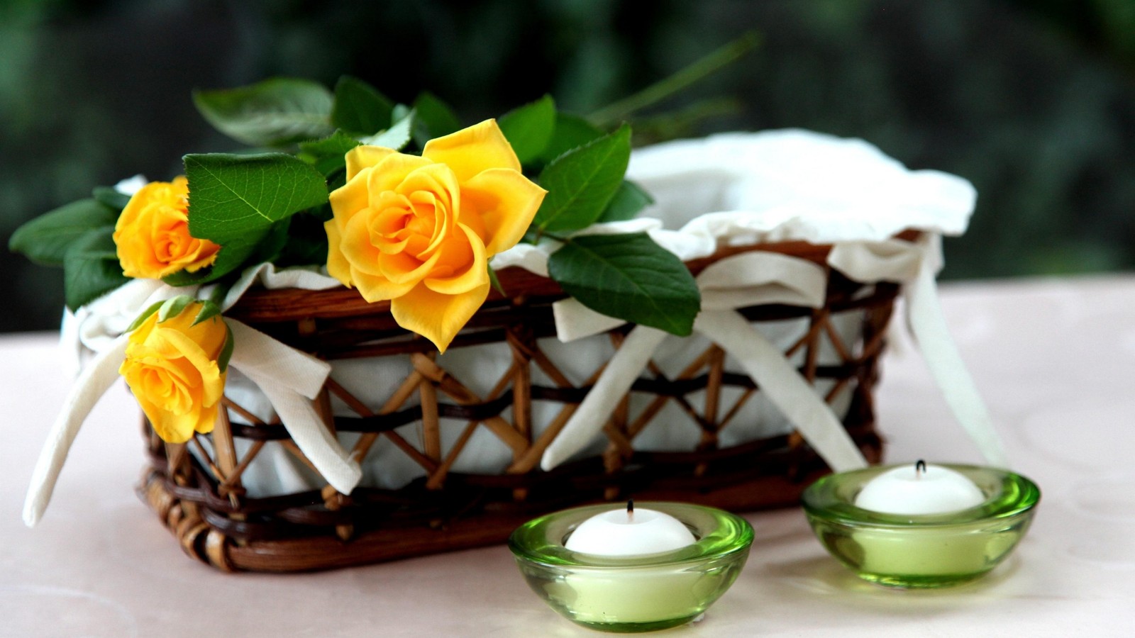 Il y a deux bougies et un panier avec des roses jaunes dedans (jaune, rose, pièce maîtresse, bouquet de fleurs, fleuristerie)