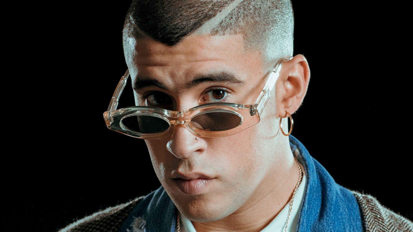 Un gros plan d'un homme avec des lunettes sur le visage (bad bunny, arrière plan noir, rappeur portoricain, musique, autres)