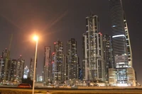 Illuminated skyline of a bustling metropolis featuring towering skyscrapers against a night sky.