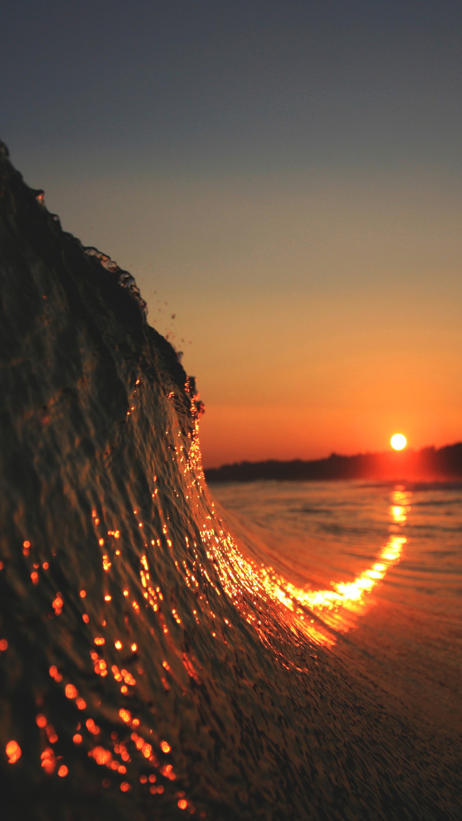 Uma onda quebrada no oceano ao pôr do sol com uma luz laranja brilhante (por do sol, âmbar, paisagem natural, água, resplendor)