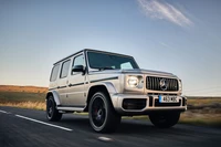 Mercedes-Benz G-Class in motion on a scenic road.