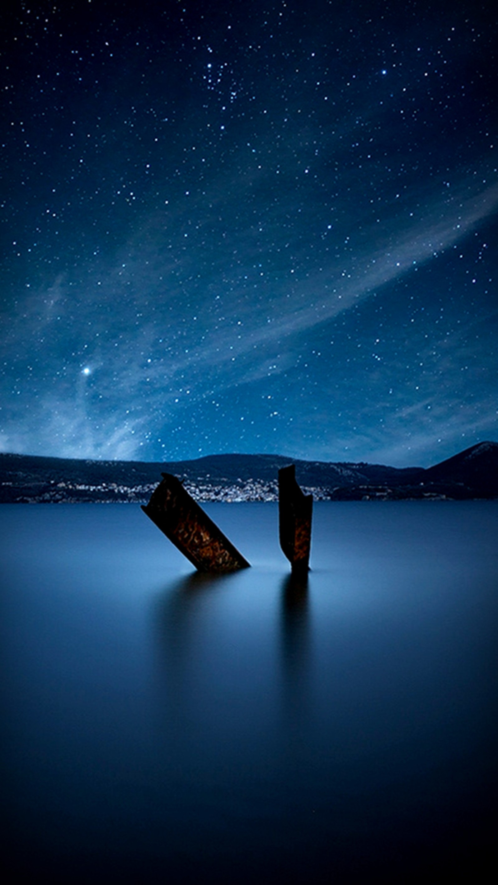 Starry night sky with two wooden posts in the water (night, sky, starry)