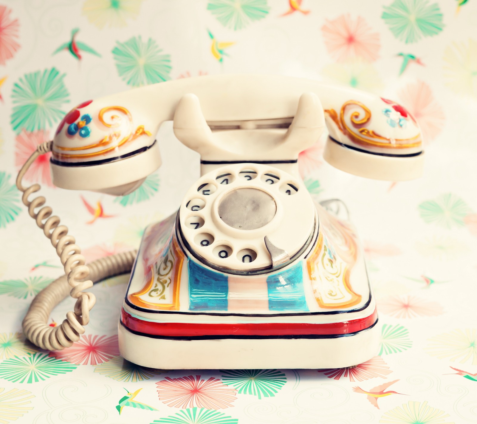 There is a white telephone with a colorful design on it (nostalgic, retro, telephone, trendy colorful, vintage)