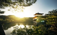 Der Kinkaku-ji Tempel bei Sonnenuntergang, der goldene Farbtöne auf dem ruhigen See reflektiert, umrahmt von üppigem Grün in Kyoto, Japan.