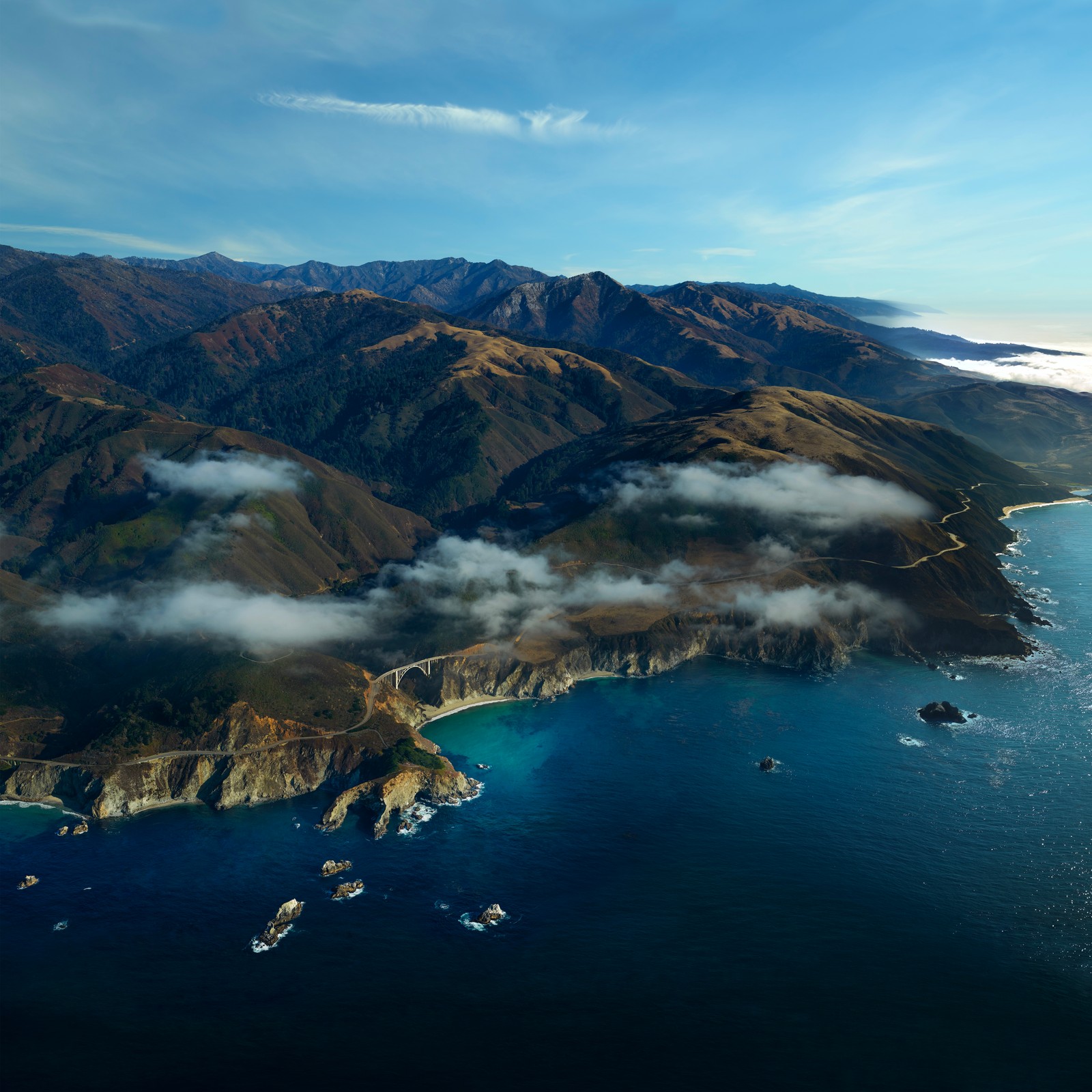 Une vue arabe d'un grand plan d'eau avec une montagne en arrière-plan (côte, macos big sur, vue aérienne, au dessus des nuages, paysage marin)