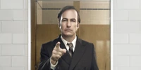 Saul Goodman en tenue formelle, gesticulant avec confiance avec un doigt pointé.