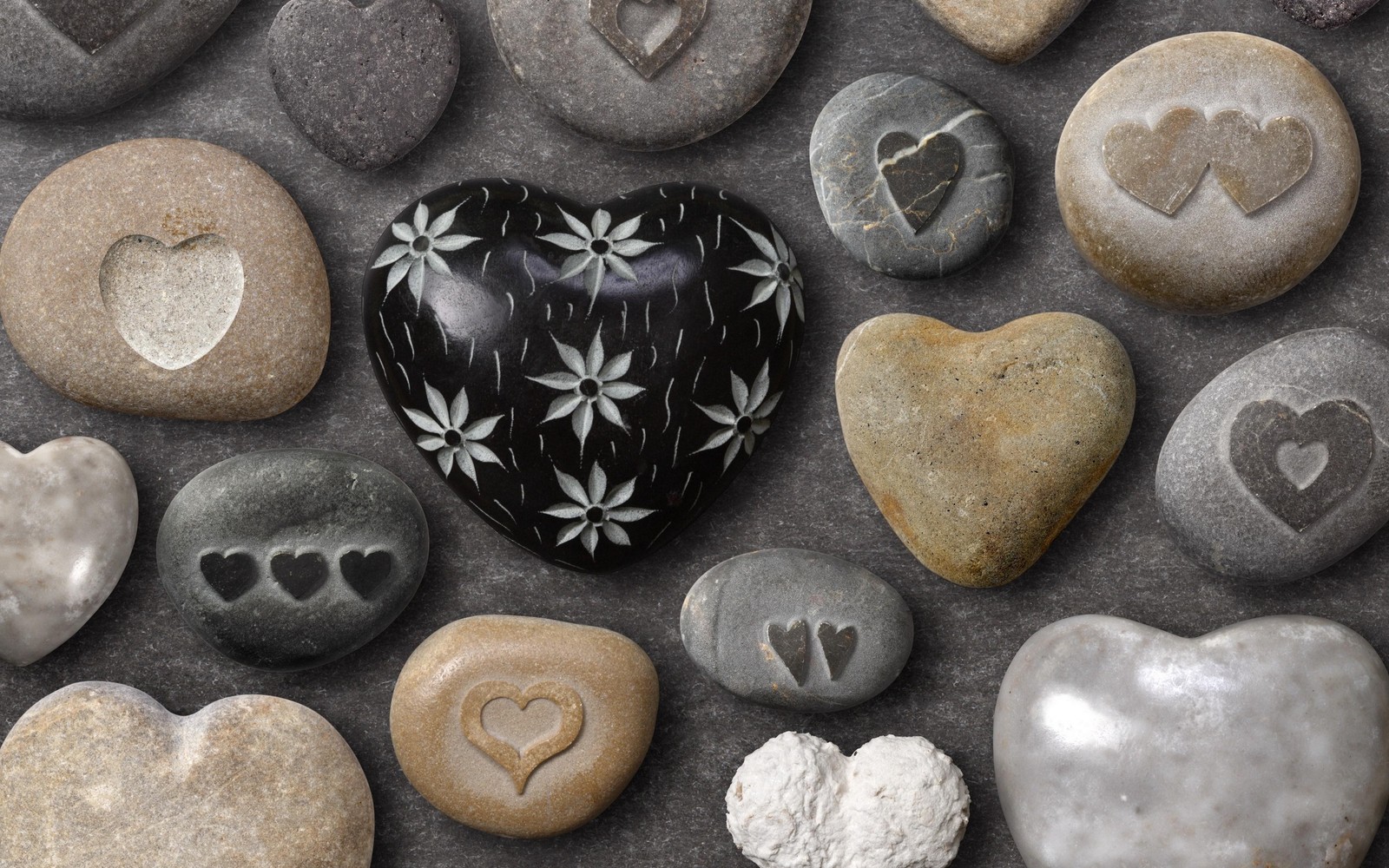 There is a heart shaped stone surrounded by rocks and stones (heart, pebble, rock, material, artifact)