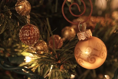 Eleganter goldener Weihnachtsornament, der an einem schön dekorierten Baum hängt, beleuchtet von warmen Lichtern.