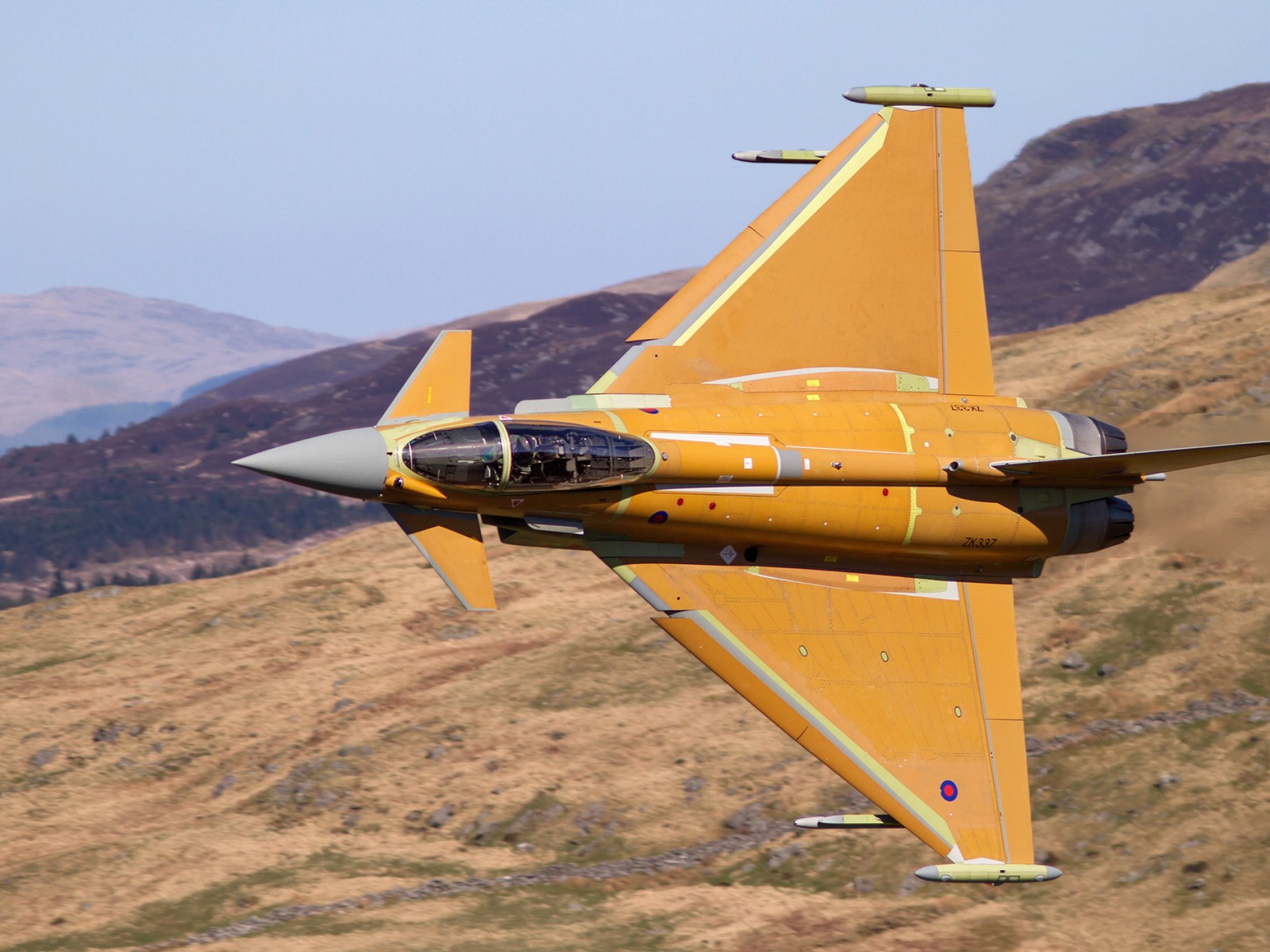 There is a yellow jet flying in the sky over a mountain (fighter aircraft, eurofighter typhoon, aircraft, military aircraft, aviation)