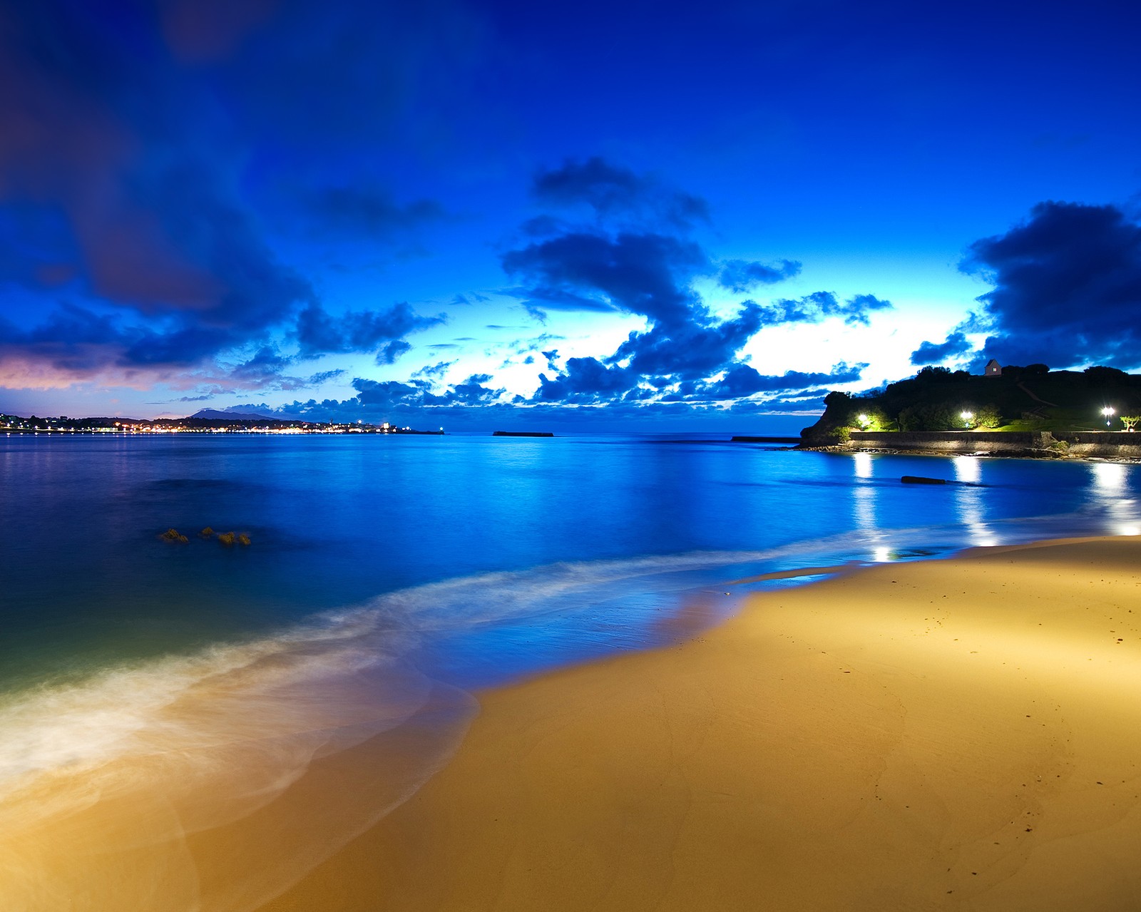 Vista arafed de una playa de noche con un barco en el agua (playa, noche, océano)