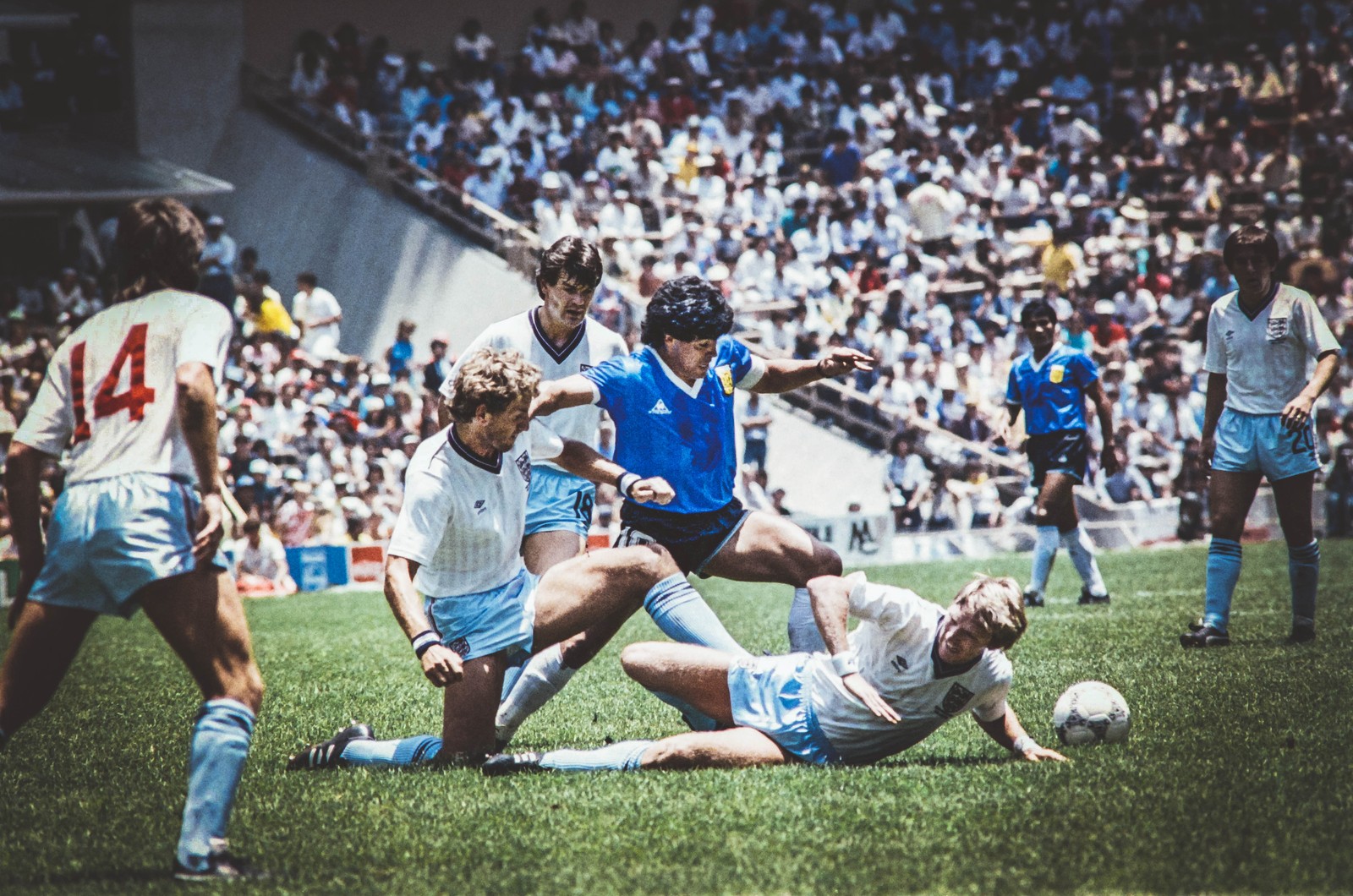 Plusieurs footballeurs jouent au football sur un terrain avec une foule qui regarde (argentine, diego armando maradona, englad, football, futbol)