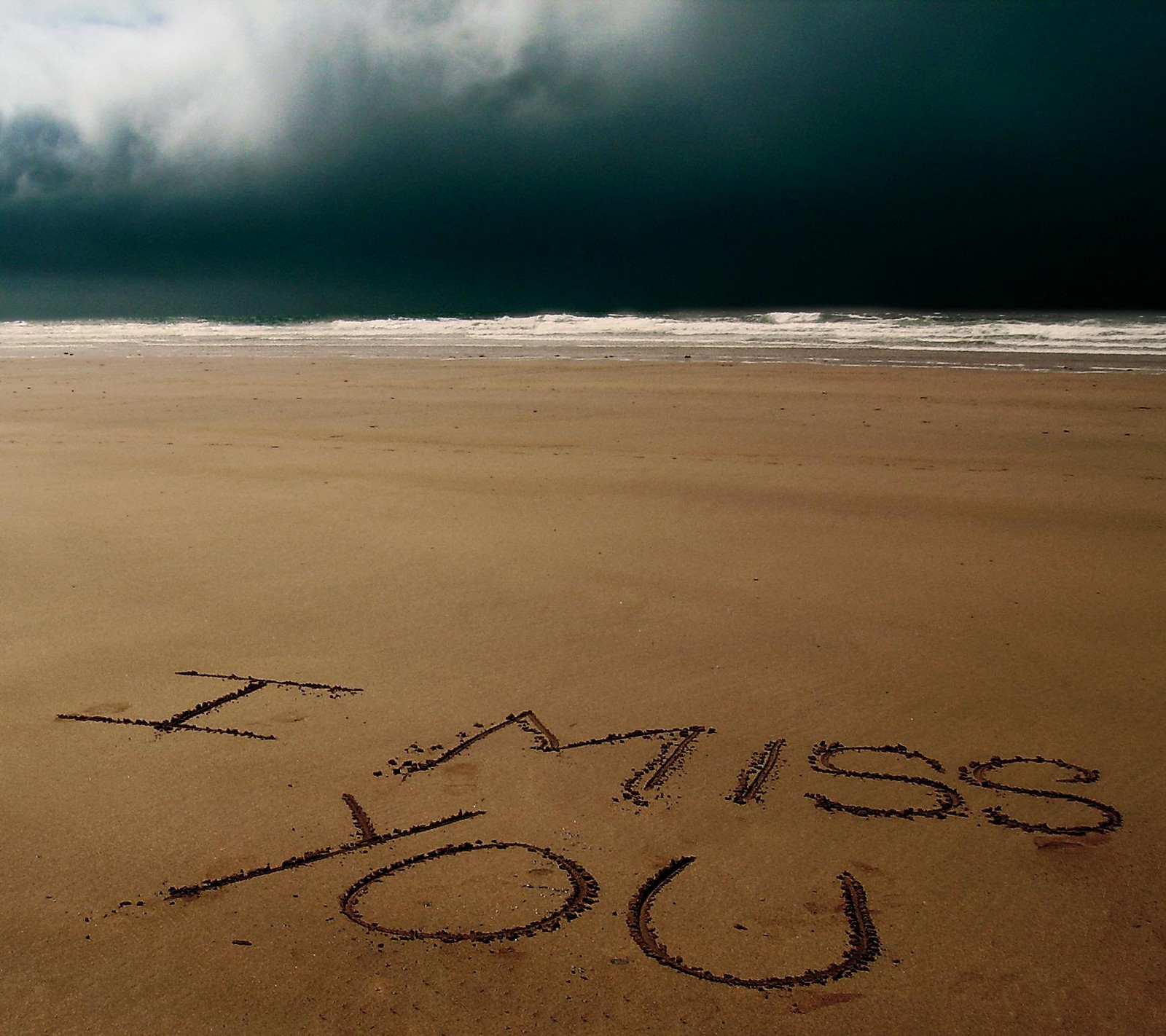 Abgerundete nachricht, die im sand an einem strand mit einem stürmischen himmel geschrieben wurde (allein, strand, herbst, inspiration, einsam)