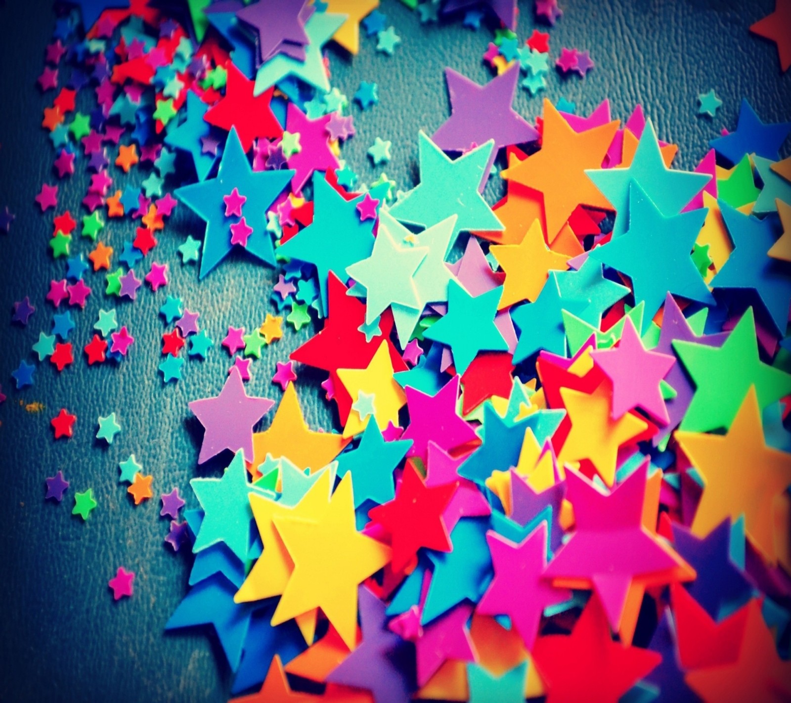 Brightly colored stars scattered on a table with a blue background (colorful, stars)