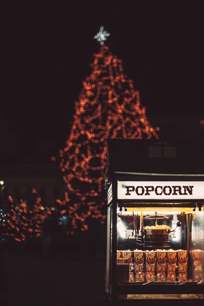 Festive Popcorn Stand with Glowing Christmas Tree at Night