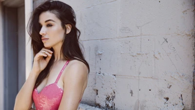 Elegant beauty captured in a thoughtful pose against a textured wall.