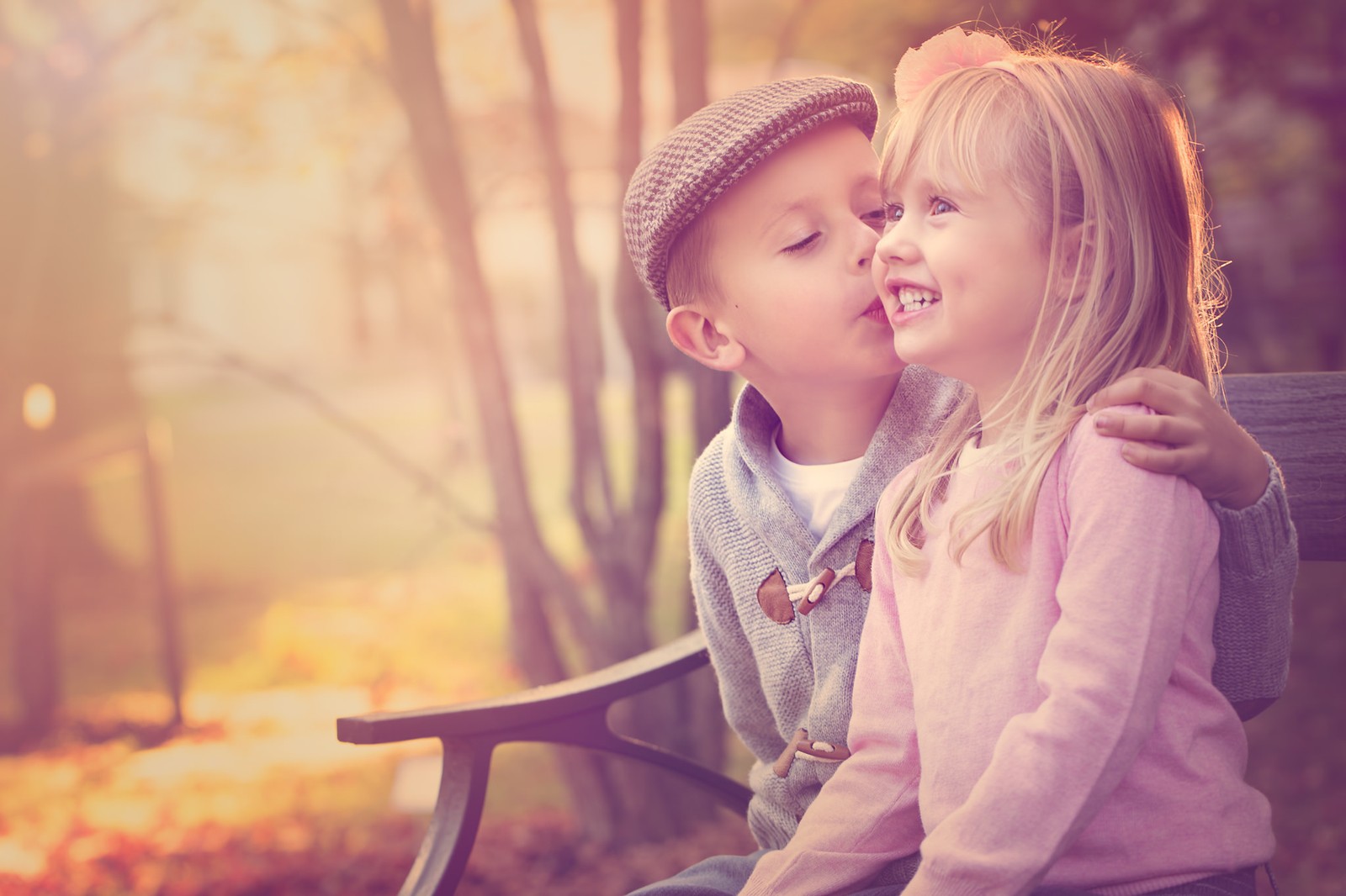 Zwei kinder sitzen auf einer bank im wald (kuss, kind, liebe, haut, schönheit)