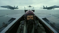 Maverick no cockpit com caças em formação sobre o oceano