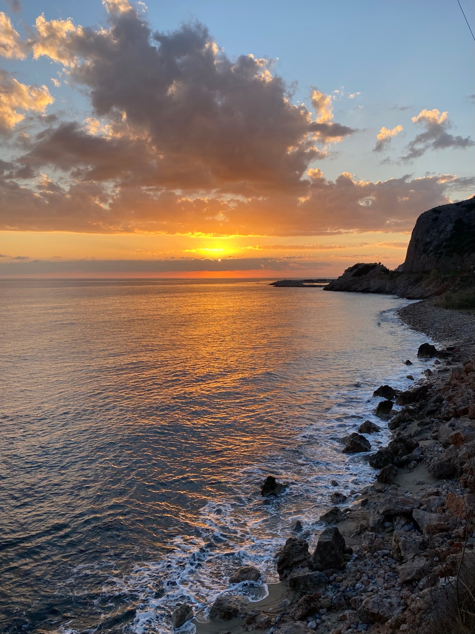 Coucher de soleil sur l'océan avec une plage et une côte rocheuse (mer, nuage, eau, ressources en eau, atmosphère)