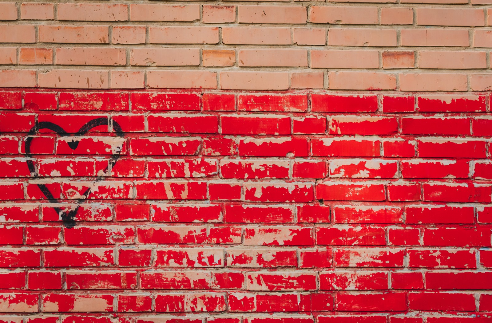 Un primer plano de una pared de ladrillo rojo con un corazón dibujado. (ladrillo, mampostería, pared, rojo, muro de piedra)