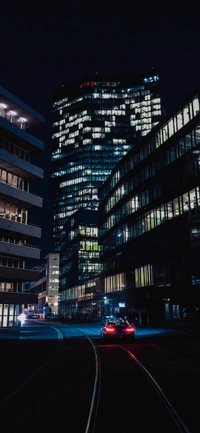 Paisaje nocturno urbano: Rascacielos iluminado con iluminación automotriz