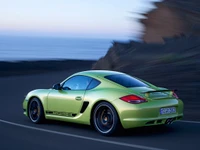 Porsche Cayman vert vif sur la route côtière au coucher du soleil