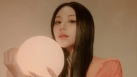 Chaeyoung de TWICE sosteniendo un orbe brillante, exudando una presencia serena y cautivadora.