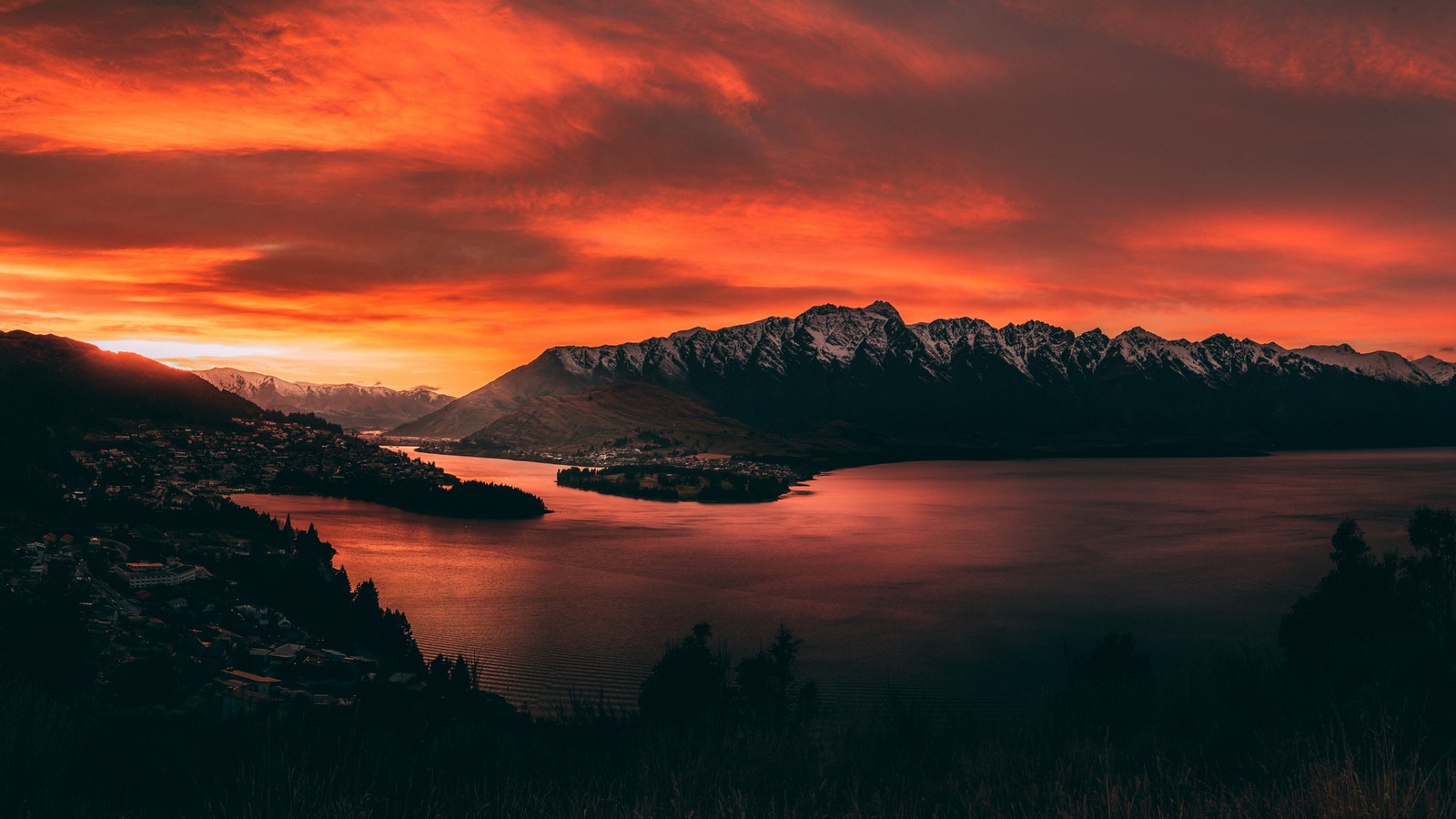 Um céu vermelho sobre um lago e montanhas com uma cadeia de montanhas ao fundo (nova zelândia, new zealand, por do sol, nuvem, água)