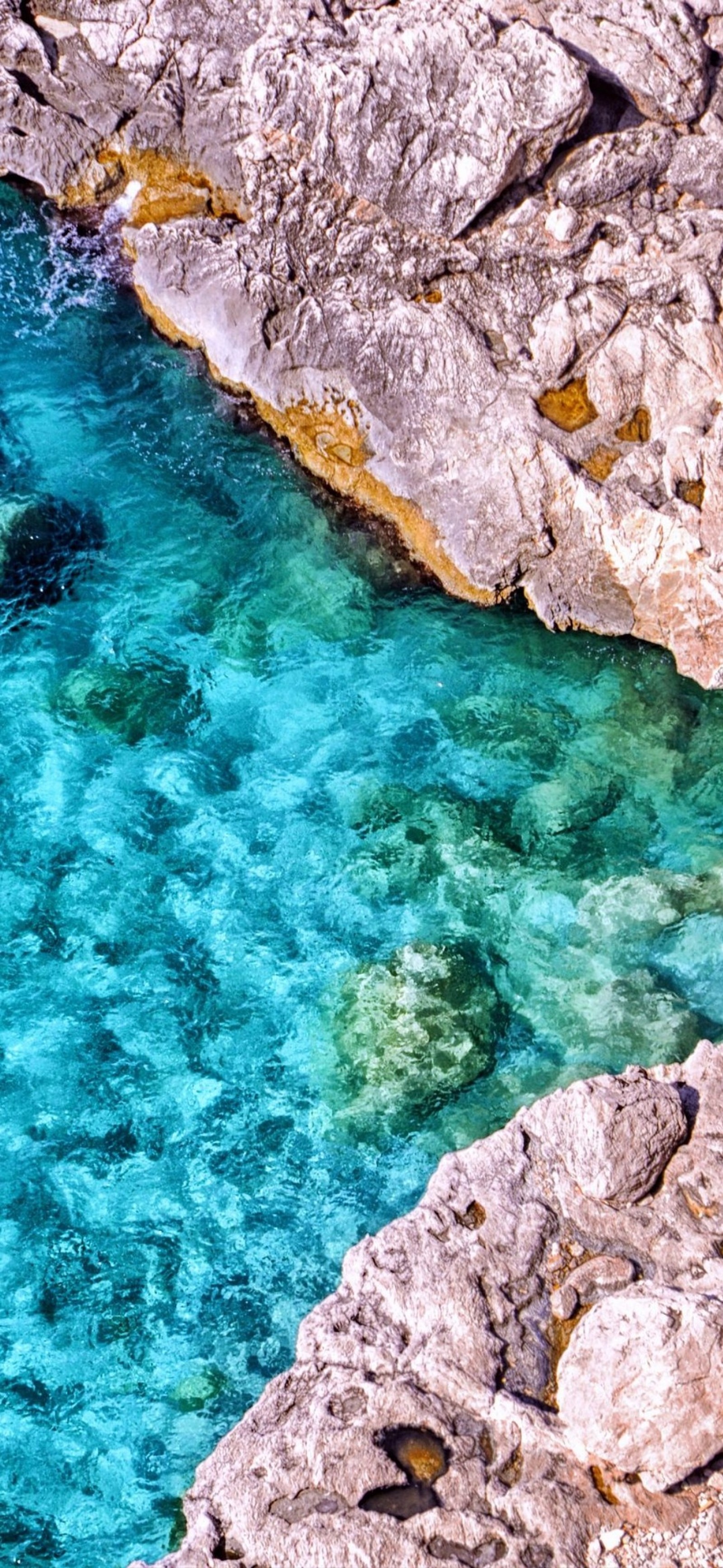 Há um barco flutuando na água perto das rochas (rocha, recursos hídricos, água, azul celeste, verde)