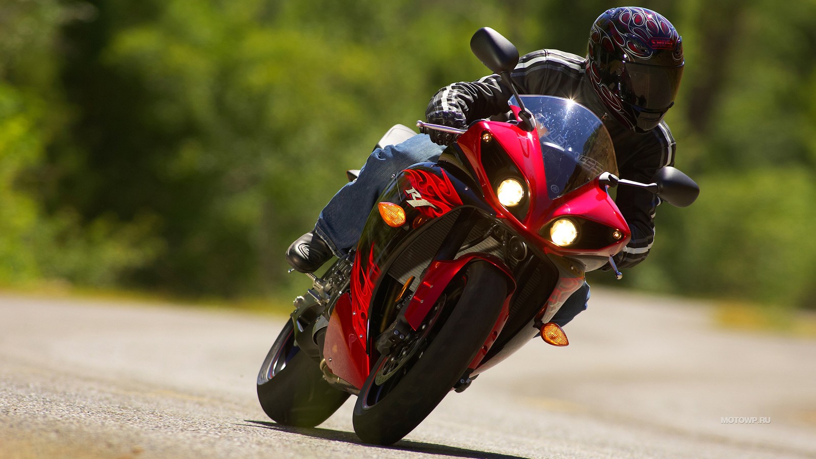 Il y a un homme à moto sur une route avec des arbres en arrière-plan (voiture, course de superbike, casque de moto, moto, casque)