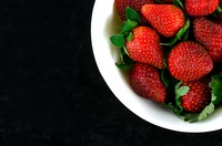 Fresh, vibrant strawberries in a white bowl, showcasing their natural sweetness and healthy appeal.