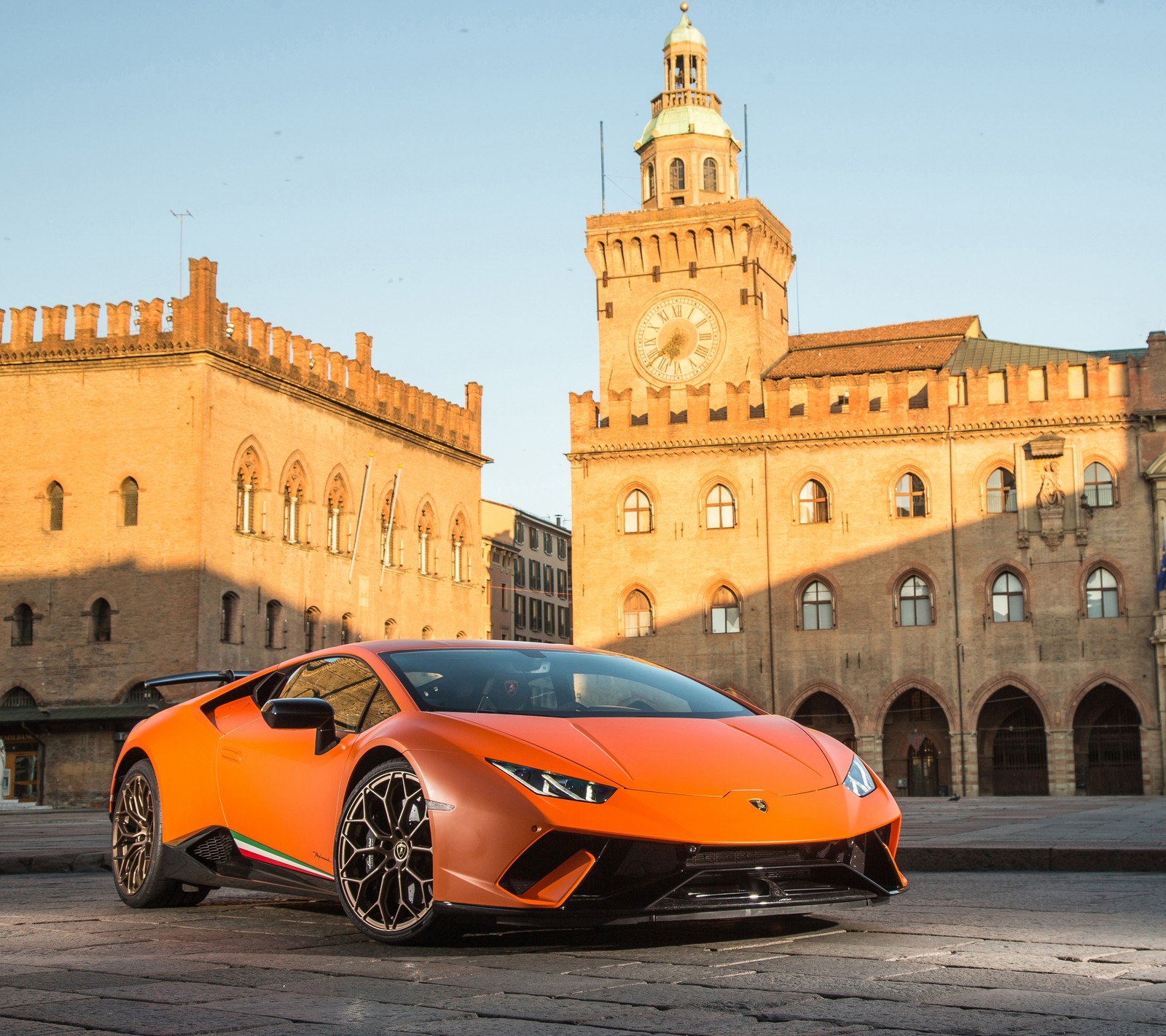 Un primer plano de un lamborghini estacionado frente a un edificio (huracan, italia, lamborghini, naranja, supercoche)