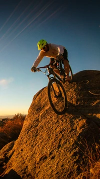 Ciclista de montanha navegando uma descida rochosa ao pôr do sol