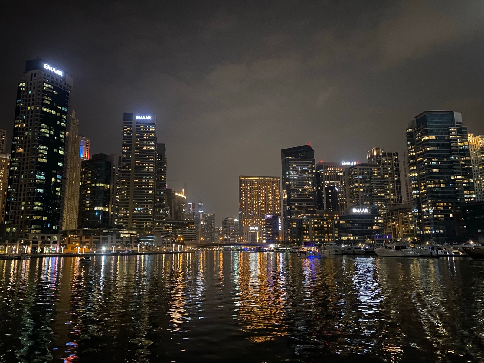 Arafly lit city skyline at night with boats in the water (dubai, cityscape, tower block, night, city)