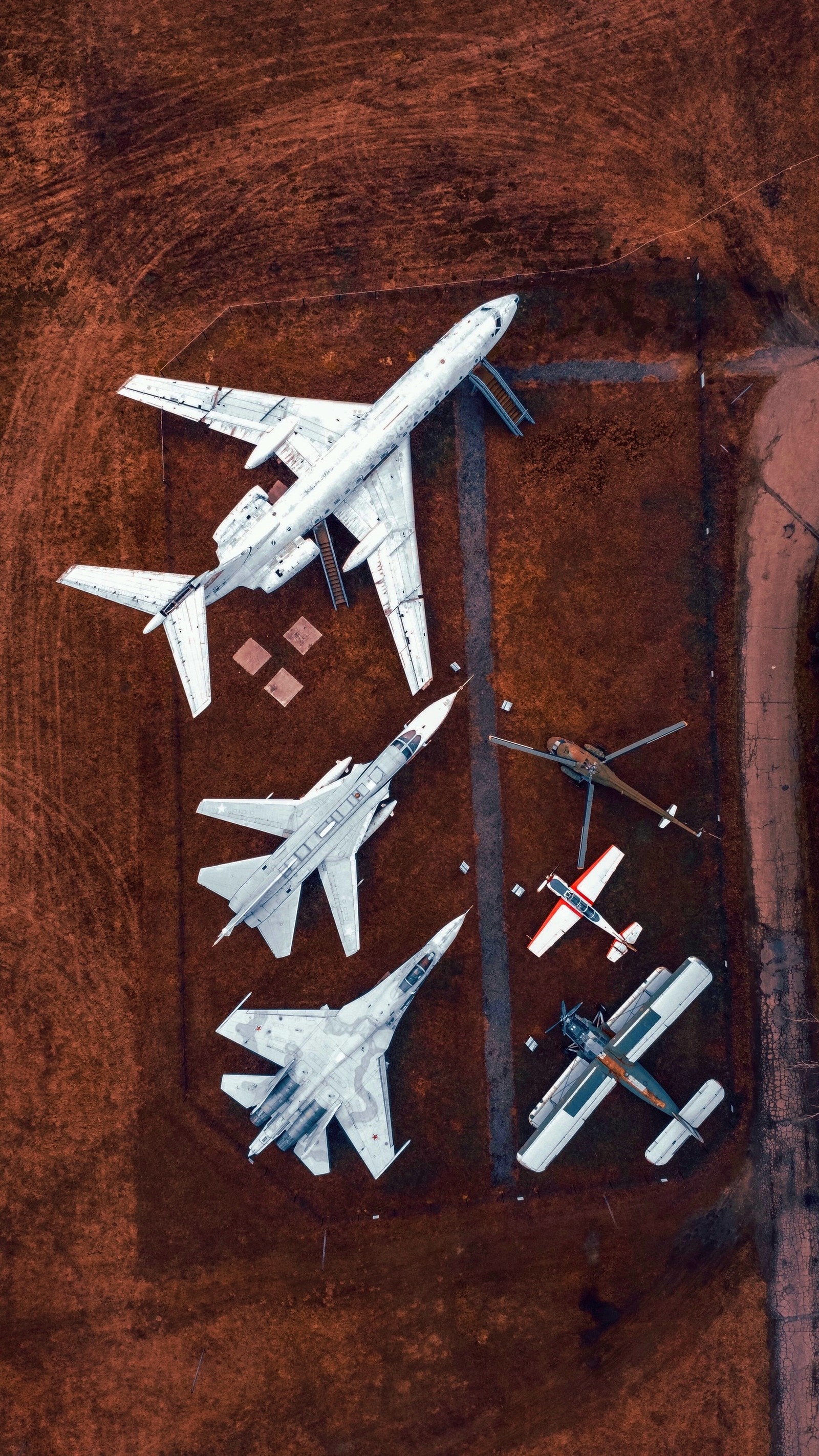 Varios aviones están estacionados en un campo de tierra con un avión en el medio (aeronave, avión, vuelo, avión a reacción, aerolínea)