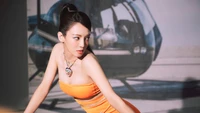 Hyoyeon in a striking orange dress poses confidently against a helicopter backdrop, embodying the essence of K-pop glamour.