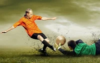 Dynamic soccer action: a player in an orange jersey attempts a kick as the goalkeeper in green dives to block the ball.