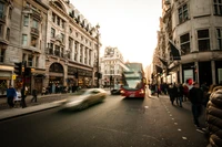 Belebte Londoner Straße mit einem Doppeldeckerbus und Fußgängern während des Sonnenuntergangs.